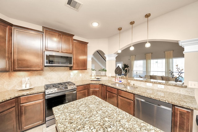 kitchen with visible vents, a sink, backsplash, stainless steel appliances, and arched walkways