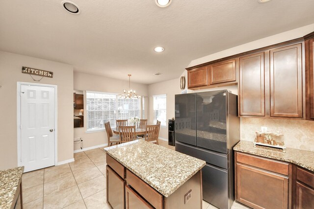 kitchen featuring light tile patterned floors, light stone counters, recessed lighting, freestanding refrigerator, and a center island