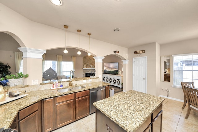 kitchen featuring a sink, light stone countertops, light tile patterned flooring, ornate columns, and stainless steel dishwasher