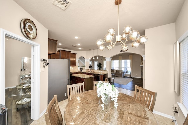 dining area featuring visible vents, recessed lighting, arched walkways, light tile patterned floors, and ornate columns