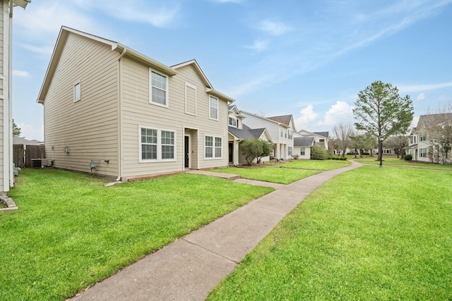 rear view of property featuring a residential view, a lawn, and cooling unit