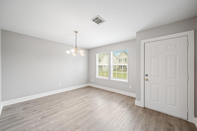 foyer entrance featuring a notable chandelier, visible vents, baseboards, and wood finished floors