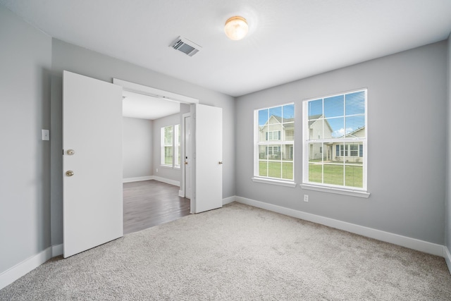 carpeted empty room featuring visible vents and baseboards