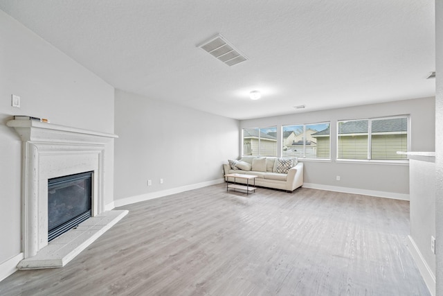 unfurnished living room featuring visible vents, wood finished floors, baseboards, and a glass covered fireplace