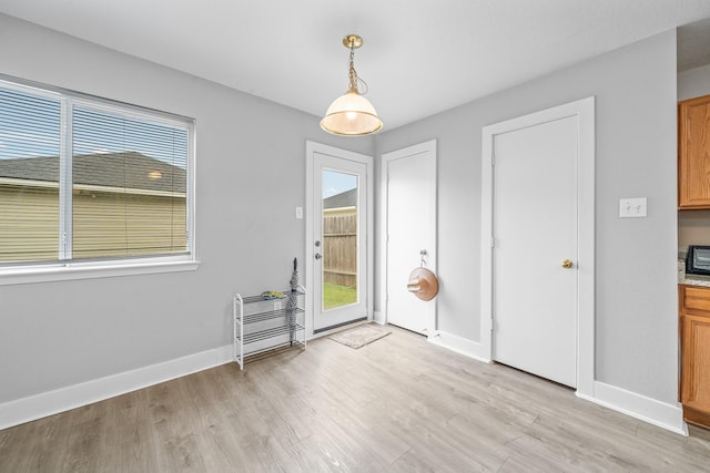 unfurnished dining area with light wood-style floors and baseboards