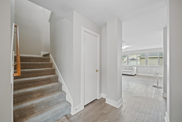 staircase with wood finished floors and baseboards