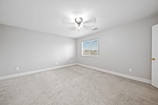 spare room with a textured ceiling, baseboards, visible vents, ceiling fan, and light carpet