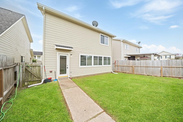 rear view of property with a lawn and a fenced backyard