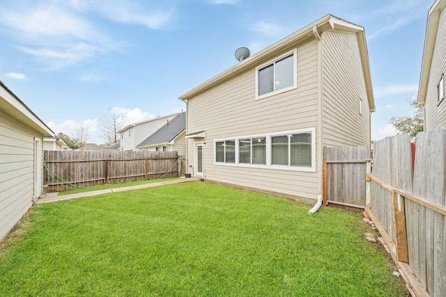 back of house with a lawn and a fenced backyard