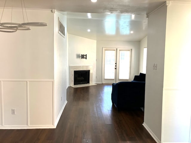 interior space with a high end fireplace, visible vents, baseboards, dark wood finished floors, and french doors