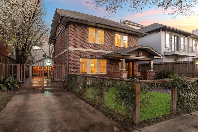 back of property featuring brick siding, a fenced front yard, and a gate