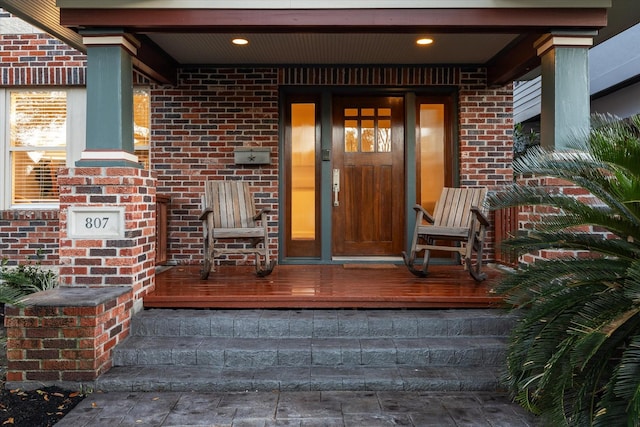 entrance to property featuring brick siding and a porch