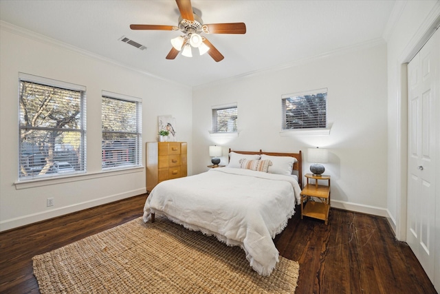 bedroom featuring baseboards, wood finished floors, visible vents, and ornamental molding