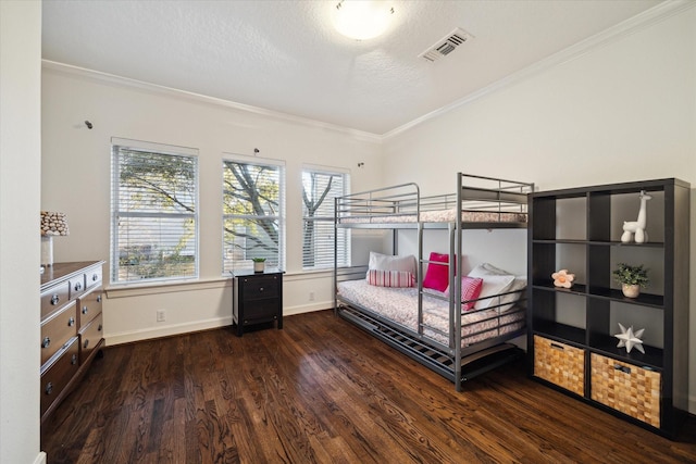 bedroom featuring wood finished floors, visible vents, baseboards, a textured ceiling, and crown molding