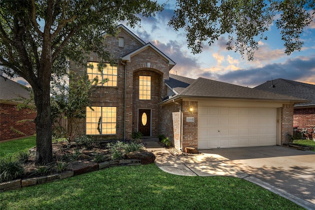 traditional home with brick siding, driveway, an attached garage, and roof with shingles