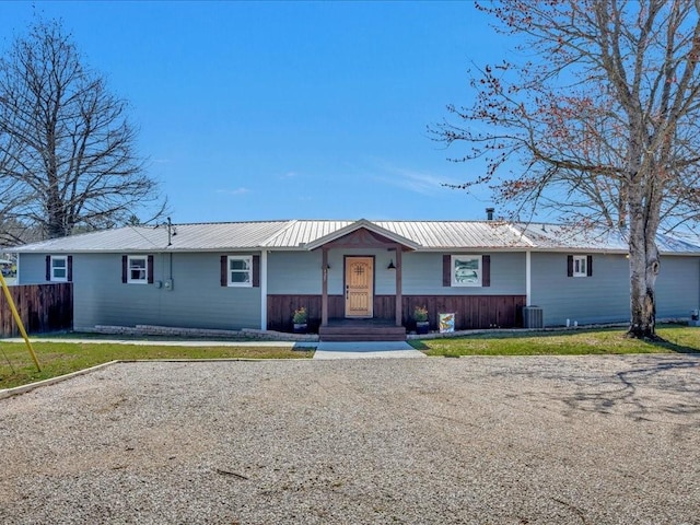 ranch-style home featuring metal roof, central air condition unit, a front lawn, and fence