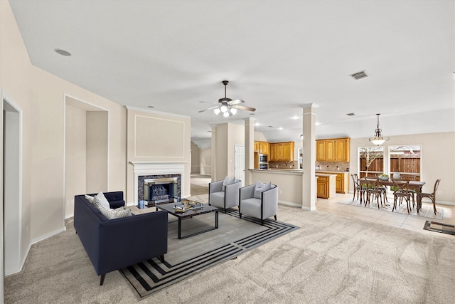 living room featuring light colored carpet, vaulted ceiling, a high end fireplace, and ornate columns