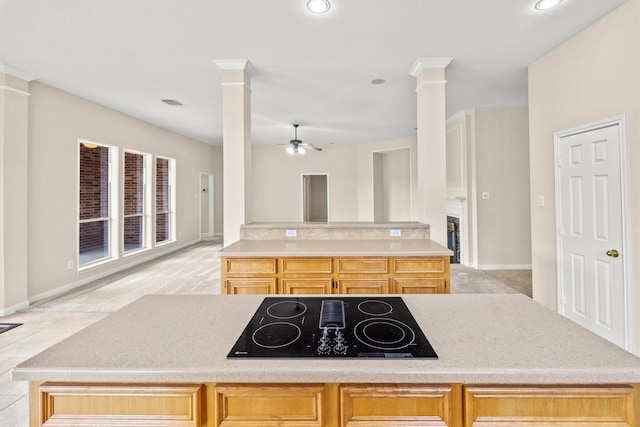 kitchen featuring ornate columns, light colored carpet, a ceiling fan, and black electric stovetop