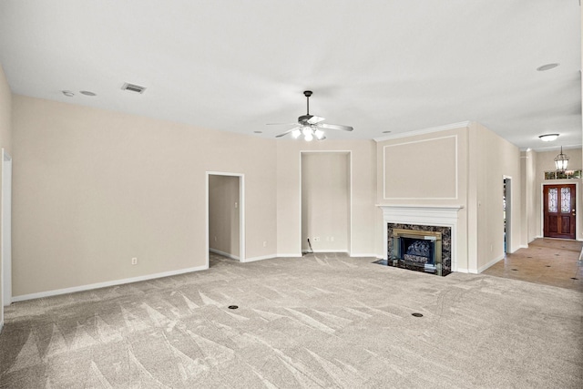 unfurnished living room featuring visible vents, a high end fireplace, carpet, baseboards, and ceiling fan