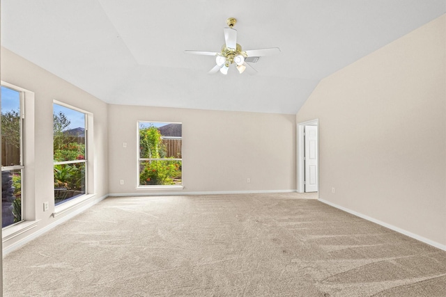 empty room with vaulted ceiling, ceiling fan, baseboards, and carpet floors