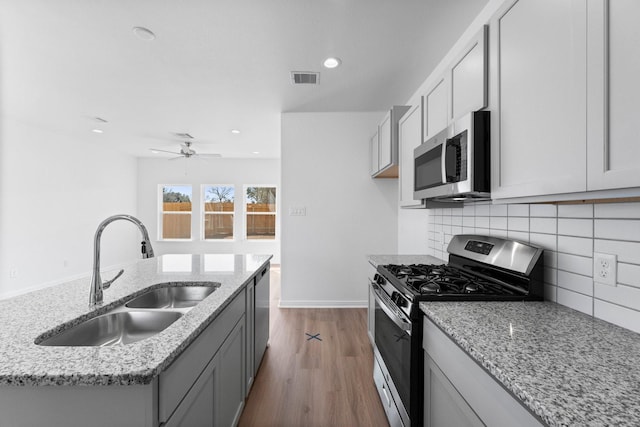 11837 E Gate Dr, Willis, TX 77318 - kitchen featuring a sink, light stone countertops, tasteful backsplash, and stainless steel appliances