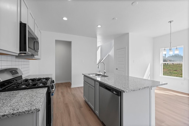 11837 E Gate Dr, Willis, TX 77318 - kitchen featuring backsplash, baseboards, light wood-type flooring, stainless steel appliances, and a sink
