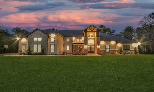 view of front of house featuring stone siding, stucco siding, and a front lawn