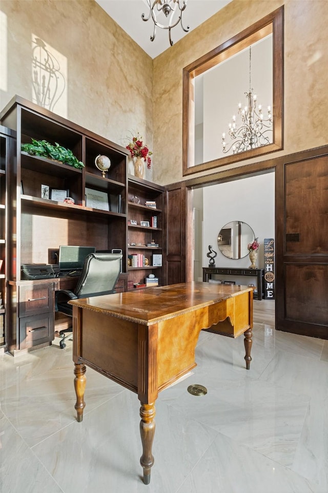 office area featuring a notable chandelier, marble finish floor, and a towering ceiling