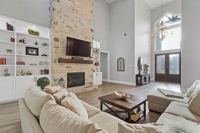 living area featuring visible vents, a fireplace, light wood-style floors, and a towering ceiling