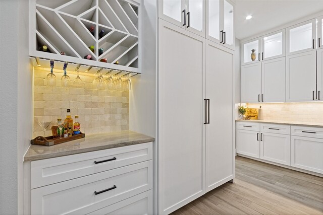 bar with a dry bar, recessed lighting, light wood-type flooring, and backsplash