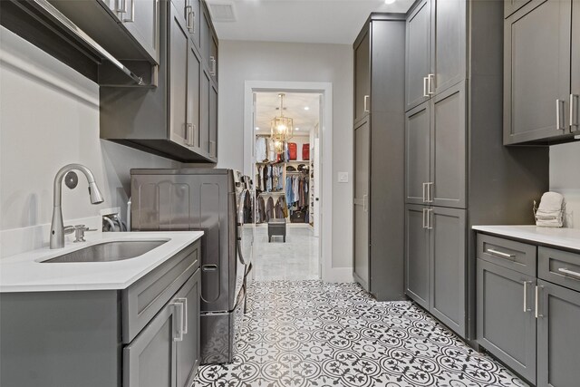 laundry area featuring light tile patterned floors, visible vents, cabinet space, a sink, and independent washer and dryer