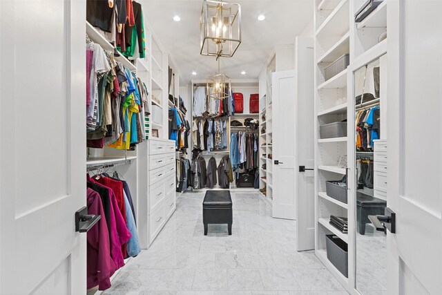 walk in closet with marble finish floor and a chandelier