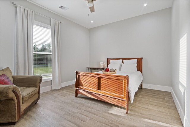 bedroom featuring visible vents, light wood-style flooring, a ceiling fan, and baseboards