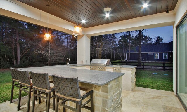 view of patio / terrace featuring a sink, fence, grilling area, outdoor wet bar, and exterior kitchen