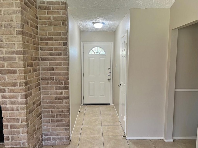 entryway with light tile patterned floors, a textured ceiling, and baseboards