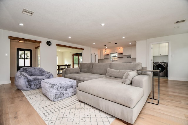 living area with washer / dryer, recessed lighting, visible vents, and light wood finished floors