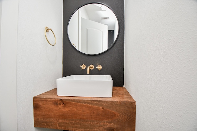 bathroom featuring a sink, visible vents, and a textured wall