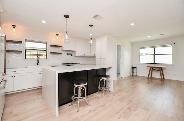 kitchen with visible vents, light wood finished floors, open shelves, light countertops, and white cabinetry