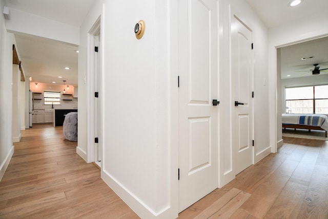 hall featuring recessed lighting, light wood-type flooring, and baseboards