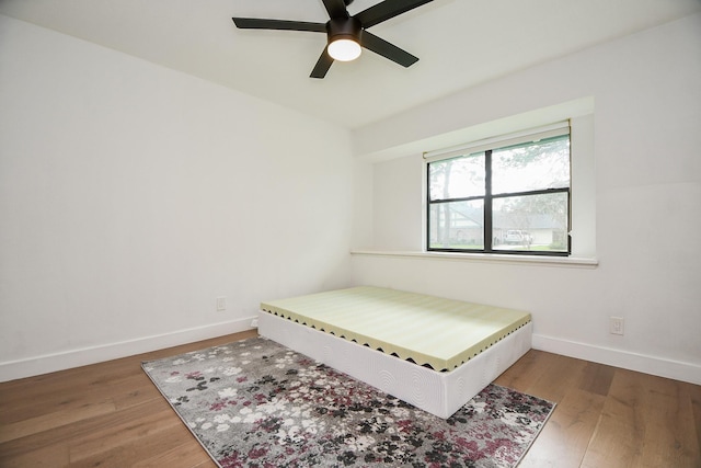 bedroom featuring wood finished floors, baseboards, and ceiling fan