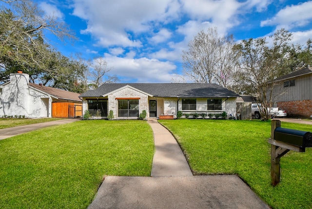 view of front facade featuring a front yard, fence, brick siding, and a shingled roof