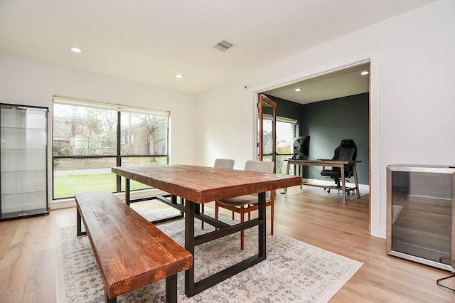 dining room with beverage cooler, light wood-style flooring, a healthy amount of sunlight, and visible vents