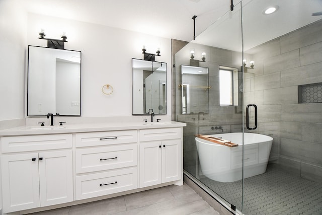 bathroom with a freestanding bath, double vanity, tile patterned floors, and a sink