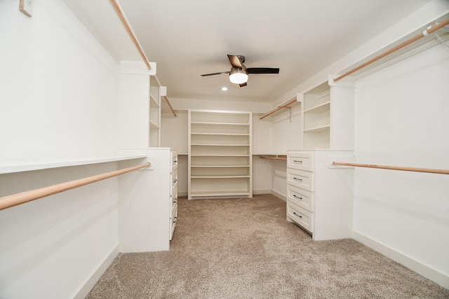 spacious closet featuring light carpet, built in desk, and a ceiling fan