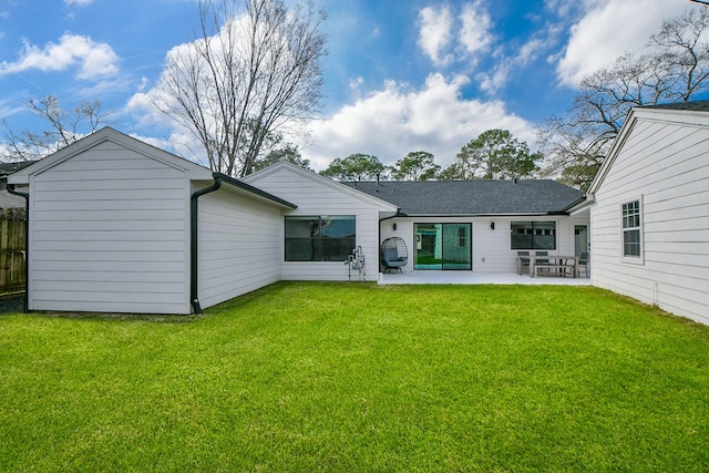 rear view of property featuring a patio, a yard, fence, and a shingled roof