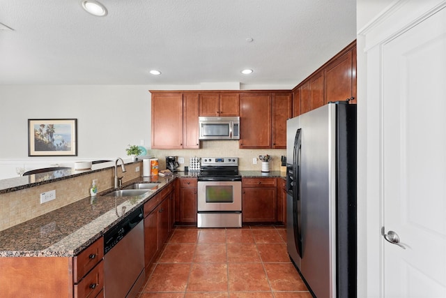26501 Mangrove Dr Unit 203, Galveston, TX 77554 - kitchen featuring appliances with stainless steel finishes, tasteful backsplash, dark stone counters, brown cabinetry, and recessed lighting