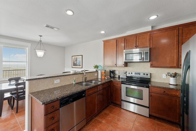 26501 Mangrove Dr Unit 203, Galveston, TX 77554 - kitchen featuring stainless steel appliances, a peninsula, backsplash, dark stone counters, and light tile patterned floors