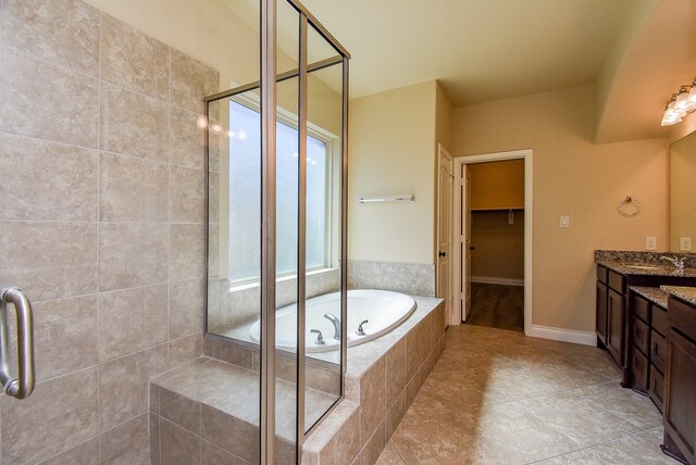 bathroom with vanity, a shower stall, a walk in closet, and a garden tub