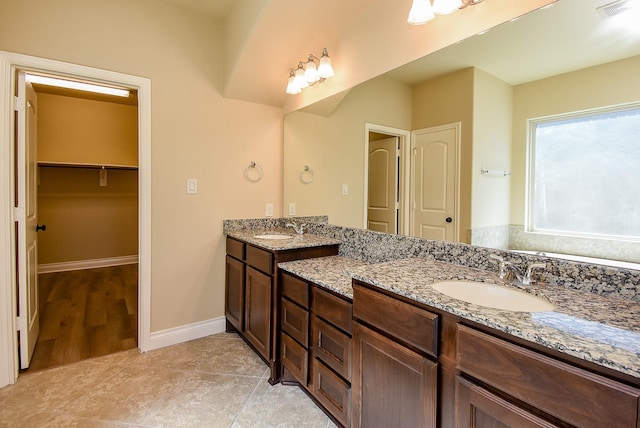 bathroom featuring a sink, visible vents, baseboards, and double vanity