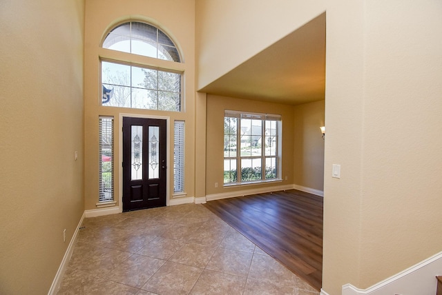 entryway with baseboards, a high ceiling, and tile patterned flooring